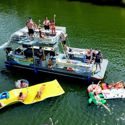 Groups of people enjoying a party on a boat and floating rafts on a lake.