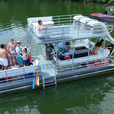 People enjoying a barge on a lake with a slide and float mat nearby.